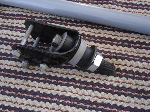 1990 Ford Bronco - A close-up view of a vehicle suspension part, possibly a shock mount or bracket, resting on a patterned carpet.