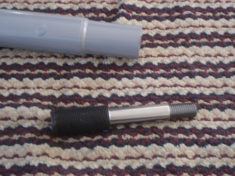 1990 Ford Bronco - A metal part with a threaded end and knurled grip rests on a textured carpet next to a gray tube.