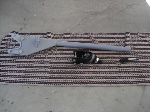 1990 Ford Bronco - A parking brake lever assembly is laid out on a striped mat next to a concrete surface.