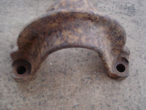 1990 Ford Bronco - A close-up view of a heavily rusted metal component, likely a vehicle part, resting on a concrete surface.