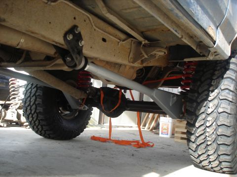 1990 Ford Bronco - The underside of a heavily modified SUV shows off its beefy suspension and large off-road tires.
