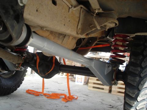 1990 Ford Bronco - Close-up of a vehicle's suspension system, showing modifications and orange tie-down straps.
