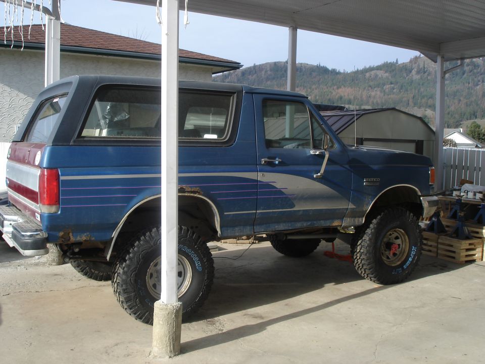 1990 Ford Bronco, blue with silver and pink stripes, lifted with aftermarket wheels