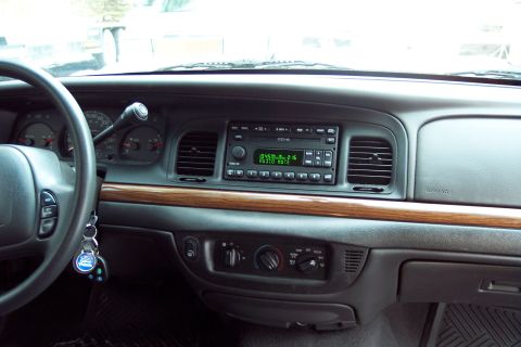 2001 Ford Crown Victoria - The interior of a 2001 Ford Crown Victoria, its dashboard with a radio and wood grain accents.