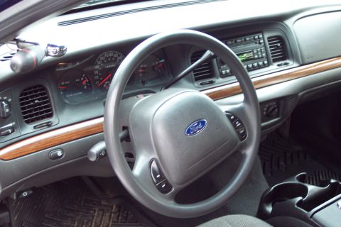 2001 Ford Crown Victoria - The dashboard of a 2001 Ford Crown Victoria features wood trim accents and a Ford-branded steering wheel.