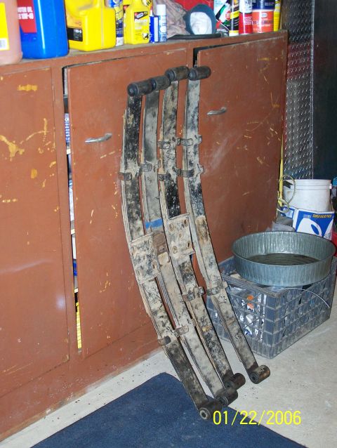 1988 Suzuki Samurai - Four used leaf springs are shown leaning against a storage cabinet, with a pan of oil on a crate nearby.