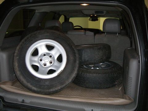 1995 Ford Bronco - Several spare tires are loaded into the cargo area of an SUV, with one tire prominently displayed on the left.