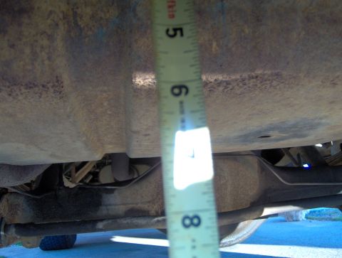 1978 Ford Bronco - A measuring tape is held against the undercarriage of a vehicle, indicating clearance.