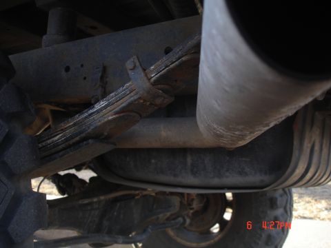 1979 Ford Bronco - Close-up of the rear suspension and exhaust system of a vehicle, with a Supermotors watermark visible.
