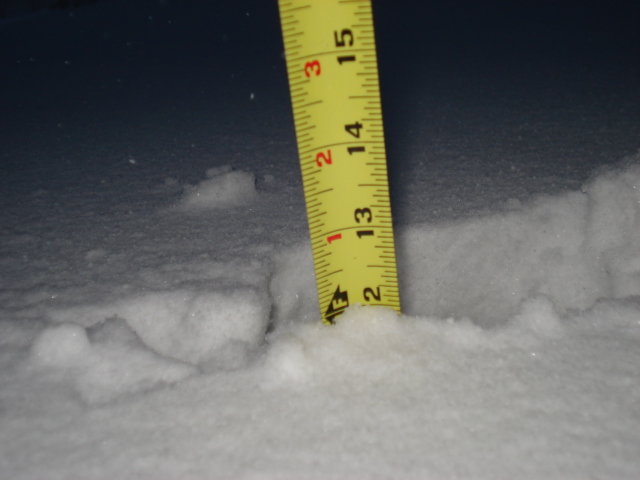 Yellow tape measure in snow, reading approximately 13 inches
