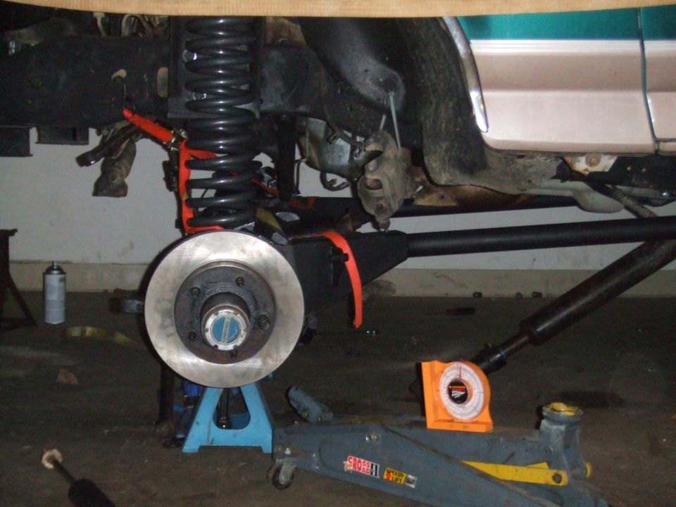 1996 Ford Bronco front suspension with disc brake rotor and coil spring. Vehicle is on jack stands