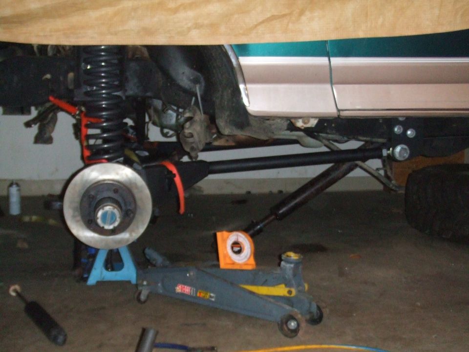 underbody of vehicle with suspension parts removed, jack stands and floor jack visible