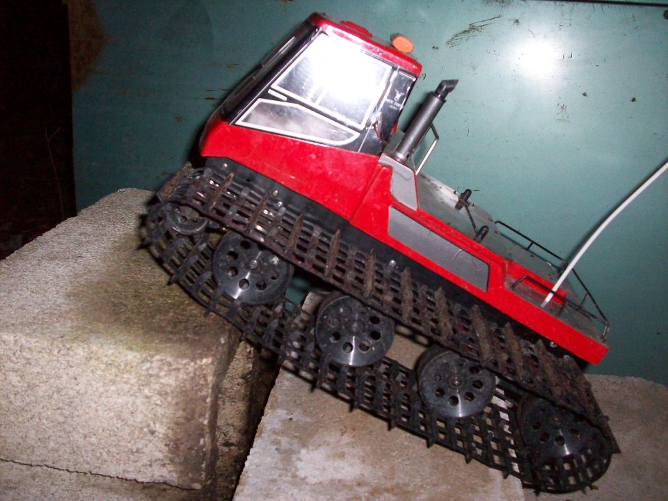 Red remote-controlled snow groomer toy on blocks