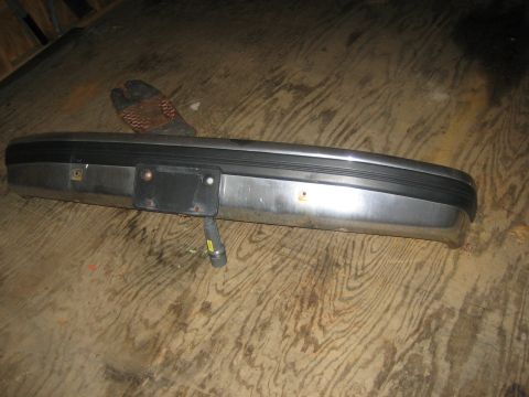 1994 Ford Bronco - Chrome bumper with license plate bracket is shown on a wooden floor.
