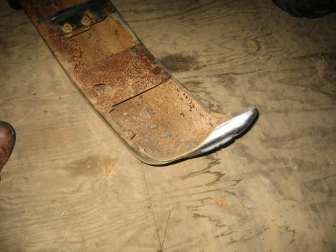 1994 Ford Bronco - A heavily rusted bumper section with a shiny chrome end is shown against a wooden floor. The Supermotors.net logo is visible in the lower r…