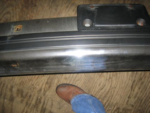 1994 Ford Bronco - A close-up of a vehicle bumper and license plate mount, with a person's foot visible.