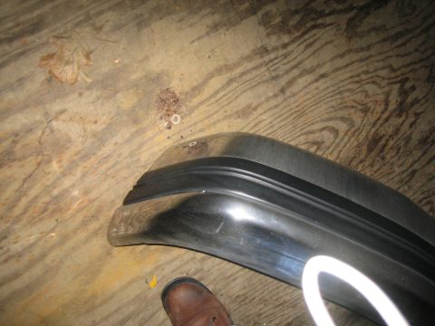 1994 Ford Bronco - A chrome bumper with a black rubber trim strip is shown resting on a wooden floor.
