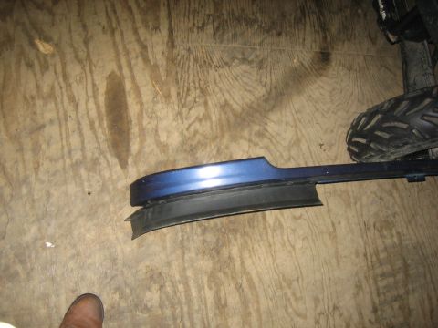1994 Ford Bronco - A blue automotive trim piece with a detached rubber seal lies on a wooden surface.