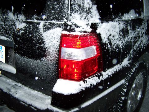 2004 Ford Expedition - A black SUV's rear taillight and bumper are covered in snow, suggesting a winter scene.