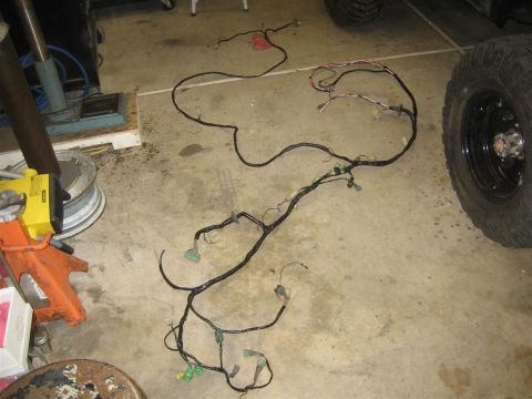 1987 Suzuki Samurai - A vehicle wiring harness is spread across a concrete floor, with a tire visible on the right side.