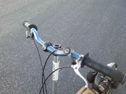 1995 Ford Bronco - Close-up view of the handlebars and controls of a scooter, showing blue handlebars and black grips.