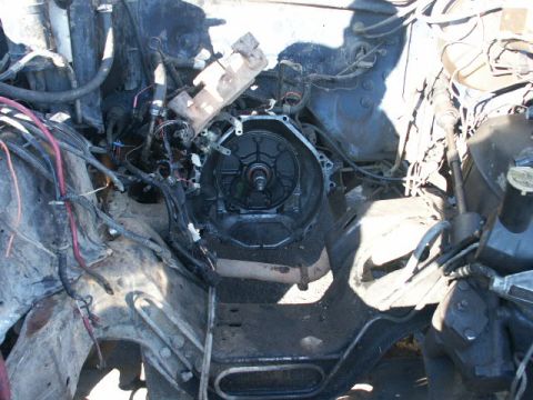 1984 Ford Bronco - The engine bay is visible with the transmission removed, revealing the bare bell housing and associated wiring and plumbing.