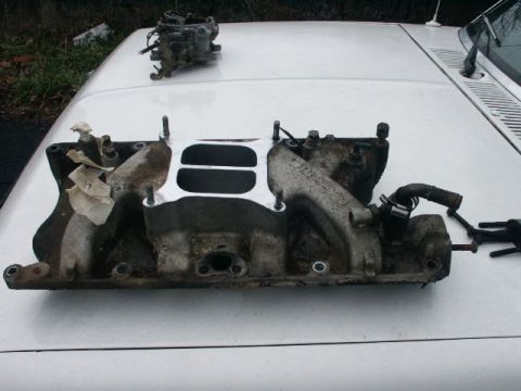 1984 Ford Bronco - Intake manifold and carburetor from a 1984 Ford Bronco sit on the vehicle's hood.