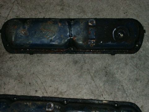 1984 Ford Bronco - A close-up view of a worn valve cover resting on a concrete surface.