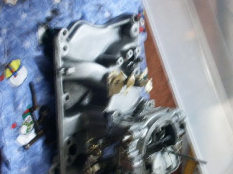 1984 Ford Bronco - An intake manifold is shown resting on a blue blanket a snowman pattern.