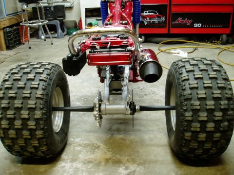 2000 Ford E350 - The rear section of a red ATV is shown with its large tires and exhaust pipe.