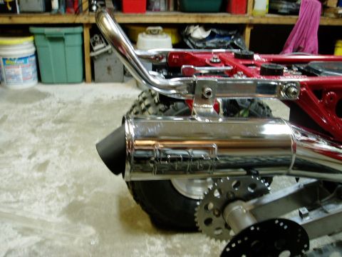2000 Ford E350 - Close-up of a chrome exhaust pipe and sprocket assembly on a red frame, with a tire visible.