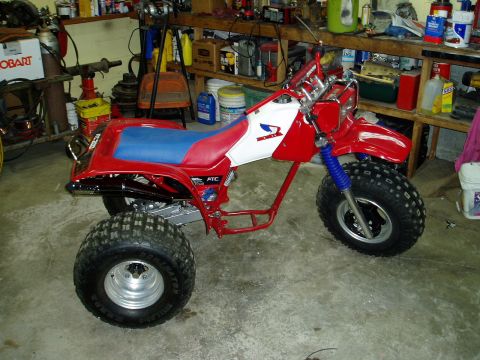 2000 Ford E350 - A red and white three-wheeled ATV sits in a cluttered garage with shelves of supplies in the background.