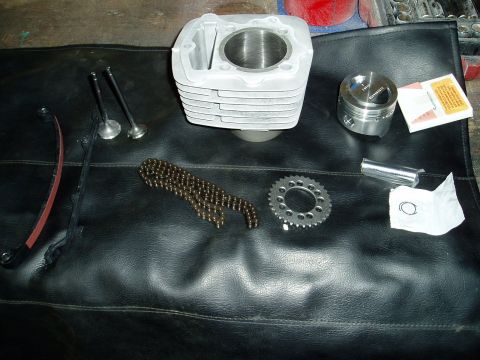 2000 Ford E350 - Various engine components including a cylinder, piston, valves, and timing chain are displayed on a black mat.