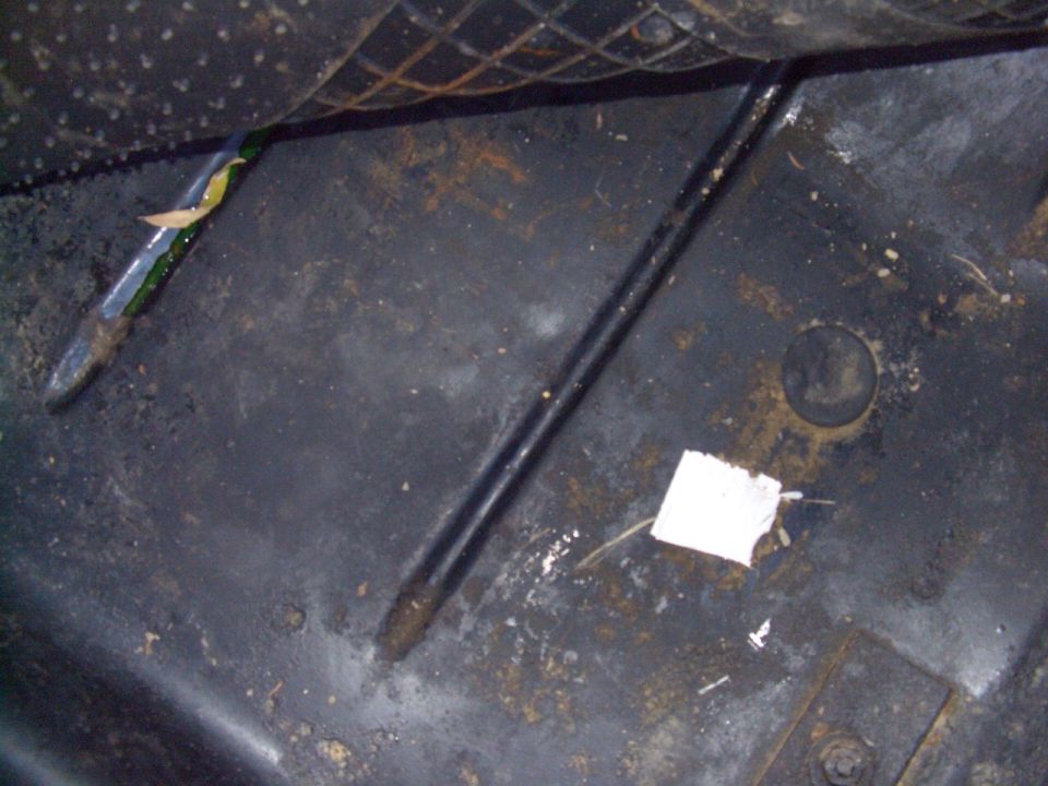 Rusty bare metal floor pan of a vehicle with stripped paint