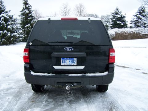 2004 Ford Expedition - Rear view of a black Ford Expedition SUV parked on a snowy road, showing its taillights and license plate.