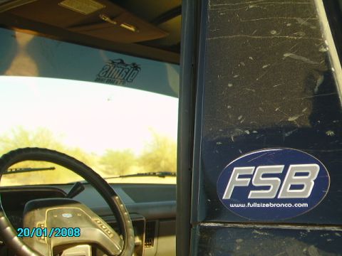 1990 Ford Bronco - The interior of a Ford Bronco shows a steering wheel and a sticker for fullsizebronco.com.