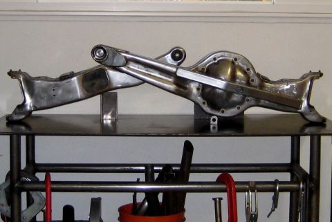1996 Ford Bronco - A Ford Twin Traction Beam front axle set up on stands on a steel welding table, stripped to bare metal with the two beams crossing over eac…
