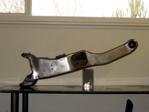 1996 Ford Bronco - A close-up view of a polished metal automotive suspension component, possibly a control arm, displayed indoors.