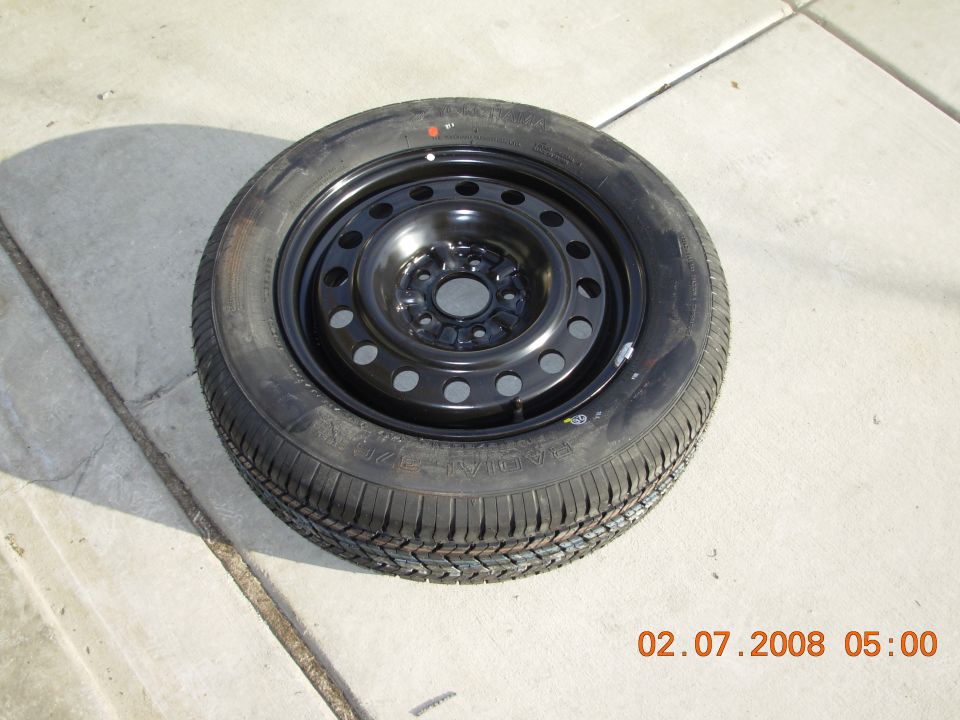 Spare tire with black steel rim on concrete surface