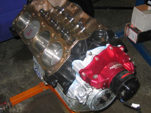 1992 Ford Mustang - Engine block on an orange stand, showing cylinder bores and a red water pump assembly.