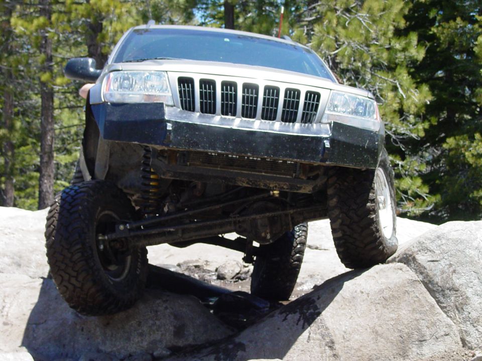 Silver 2004 Jeep Grand Cherokee off-roading on rocks, front view