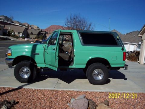 1996 Ford Bronco - Side view of a 1996 Ford Bronco, parked outdoors with its doors open.