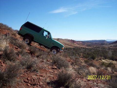 1996 Ford Bronco - A green Ford Bronco navigates a challenging off-road terrain on a sunny day.
