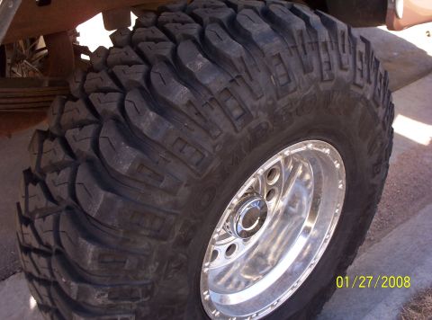 1995 Ford Bronco - A close-up view of a large, aggressive off-road tire mounted on a shiny chrome wheel.