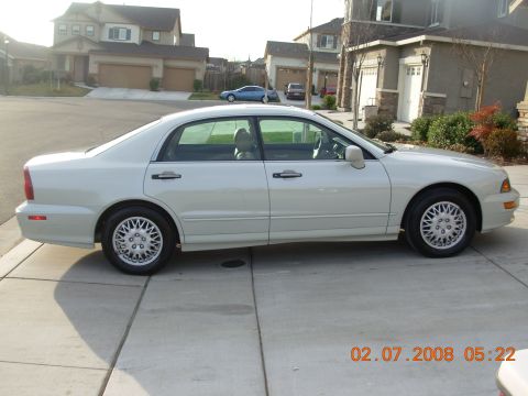 1995 Ford Taurus - A white sedan is parked on a concrete driveway in front of houses.