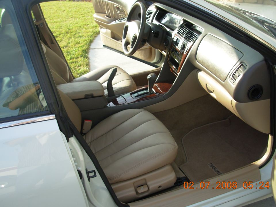 Interior view of a beige car with wood trim and leather seats. Floor mat reads 'DIAMANT'