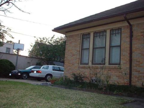 1996 Ford Taurus - A white 1996 Ford Taurus is parked next to a dark sedan in front of a brick house.