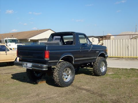 1989 Ford Bronco - Lifted 1989 Ford Bronco with a removable top, parked outdoors with another vehicle nearby.