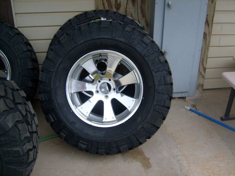 1989 Ford Bronco - Several off-road tires with shiny chrome wheels are displayed, with a Supermotors.net watermark visible.