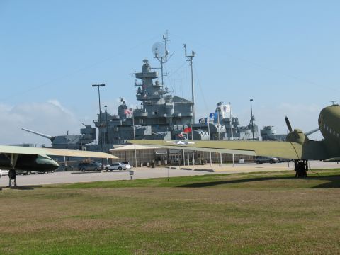 1997 Ford Crown Victoria - A large battleship and two aircraft are on display under a clear blue sky.